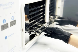 Loading nail tools into a professional dry heat sterilizer.